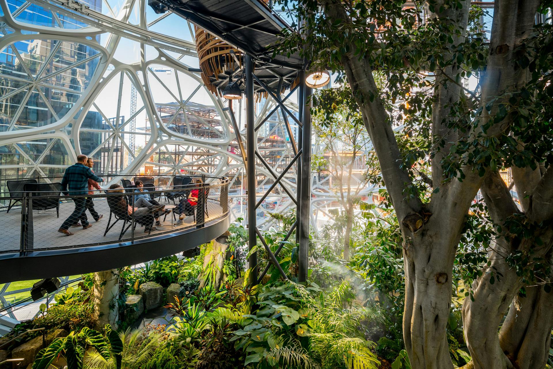 Photograph by Stuart Isett. ©2018 Stuart Isett. All rights reserved.

March 10th, 2018 — Seattle, WA, USA


The Amazon Spheres are three spherical conservatories on the headquarters campus of Amazon in Seattle, Washington, US. Designed by NBBJ, the three glass domes are covered in pentagonal hexecontahedron panels and serve as an employee lounge and workspace. The domes, which range from three to four stories tall, house 40,000 plants as well as meeting space and retail stores. They are located under the Day 1 building on Lenora Street. The complex opened to Amazon employees and limited public access on January 30, 2018. The spheres are reserved mainly for Amazon employees, but are open to the public through weekly headquarters tours and an exhibit on the ground floor.

The plants inside were laid out and designed by Seattle landscape architects, Site Workshop. The spheres have 40,000 plants from 50 countries and are divided into three areas, with the western and eastern domes segregated into the Old World and New World.The domes are kept at a temperature of 72 °F (22 °C) and 60 percent humidity during the daytime. Amazon employed a full-time horticulturalist to grow the building's 40,000 plants over a three-year period at a greenhouse in Redmond. Amazon donated space in the greenhouse to the University of Washington's botany program during renovation of their Life Sciences Building in 2016. Among the 40 to 50 trees in the spheres, the largest is a 55-foot (17 m) Ficus rubiginosa tree, nicknamed "Rubi", which was lifted into the spheres by a crane in June 2017.

Photograph by Stuart Isett. ©2018 Stuart Isett. All rights reserved.

NBBJ, Site Workshop, amazon, biopsheres, interior, spheres

A+U